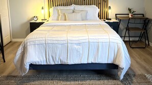 A neatly arranged bedroom with a bed, bedside tables, a desk, and a chair. - The perfect blend of comfort and convenience in our cozy studio apartment (CAPE CORAL FL)