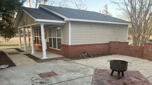 A house with a covered porch, a brick exterior, and a concrete patio.