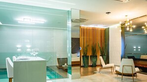 A modern hotel lobby with a glass partition, a reception desk, seating area, and a pool. - Hotel Corinto (Rio de Janeiro)