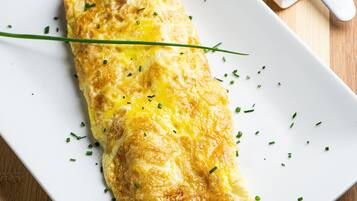 Un plato con una tortilla adornada con cebollín, sobre un plato rectangular blanco.