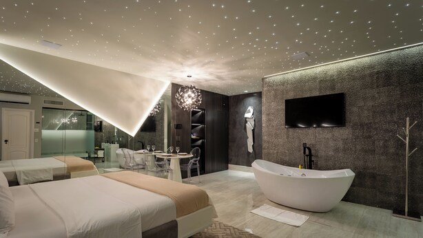 A modern hotel room with a large bed, a freestanding bathtub, a dining area, and a TV mounted on the wall. - Hotel Corinto (Rio de Janeiro)