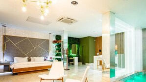 A modern hotel room with a bed, two white chairs, a wooden coffee table, a green wall with a mirror, and a pool area. - Hotel Corinto (Rio de Janeiro)