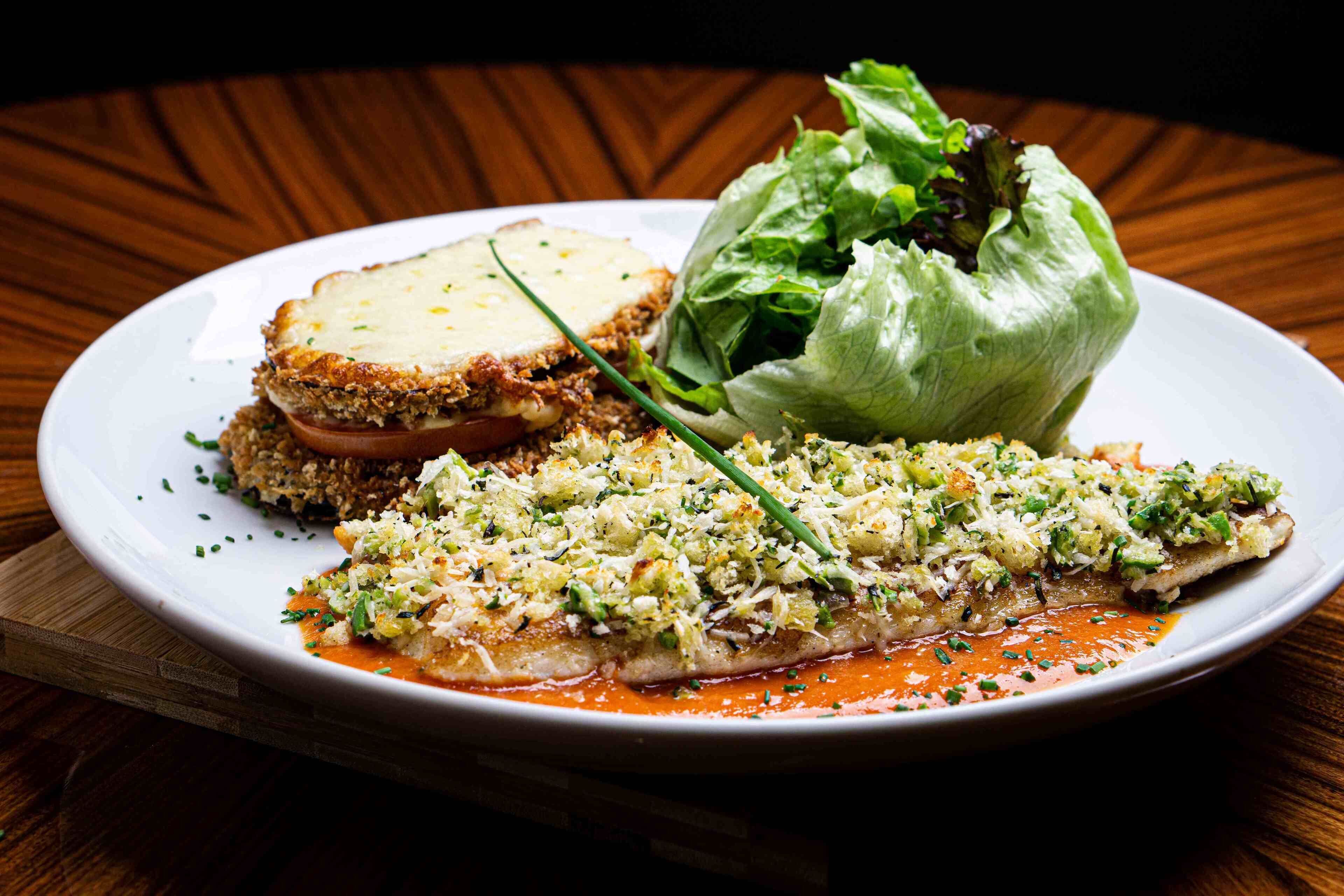 A plate with fish, bread, and a lettuce wrap.