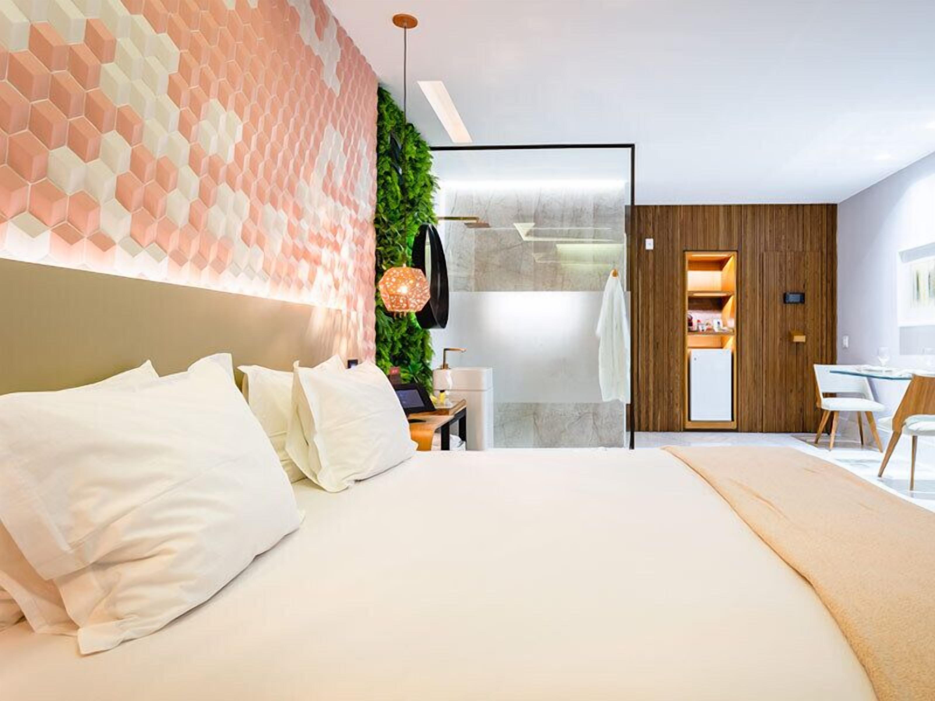 A modern bedroom with a large bed, a desk, and a green wall.