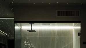 A modern bathroom with a glass-enclosed shower, a bench, and a towel rack. - Hotel Corinto (Rio de Janeiro)