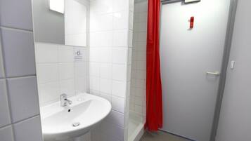 Un baño con un lavamanos blanco, un espejo y una cortina de ducha roja.