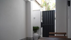 A patio with a wooden table and benches, a potted plant, and a black gate. - Our Guest House (Fiumicino)