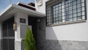 A modern building with a white exterior, a large window, and a small potted plant. - Our Guest House (Fiumicino)