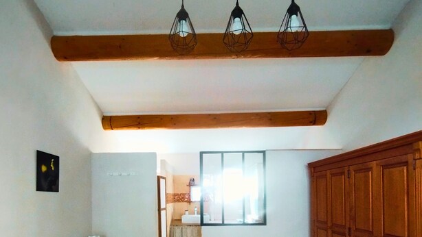 Ein Schlafzimmer mit zwei Betten, Holzbalken, einem Schrank und einem Fenster.