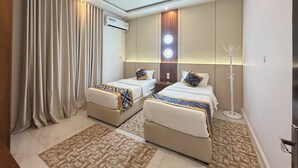 A hotel room with two beds, a ceiling light, an air conditioning unit, and a coat rack. - تميُّز الاقامة للشقق المخدومة Tamyoz Aqama for Serviced Apartments (Ha'il)