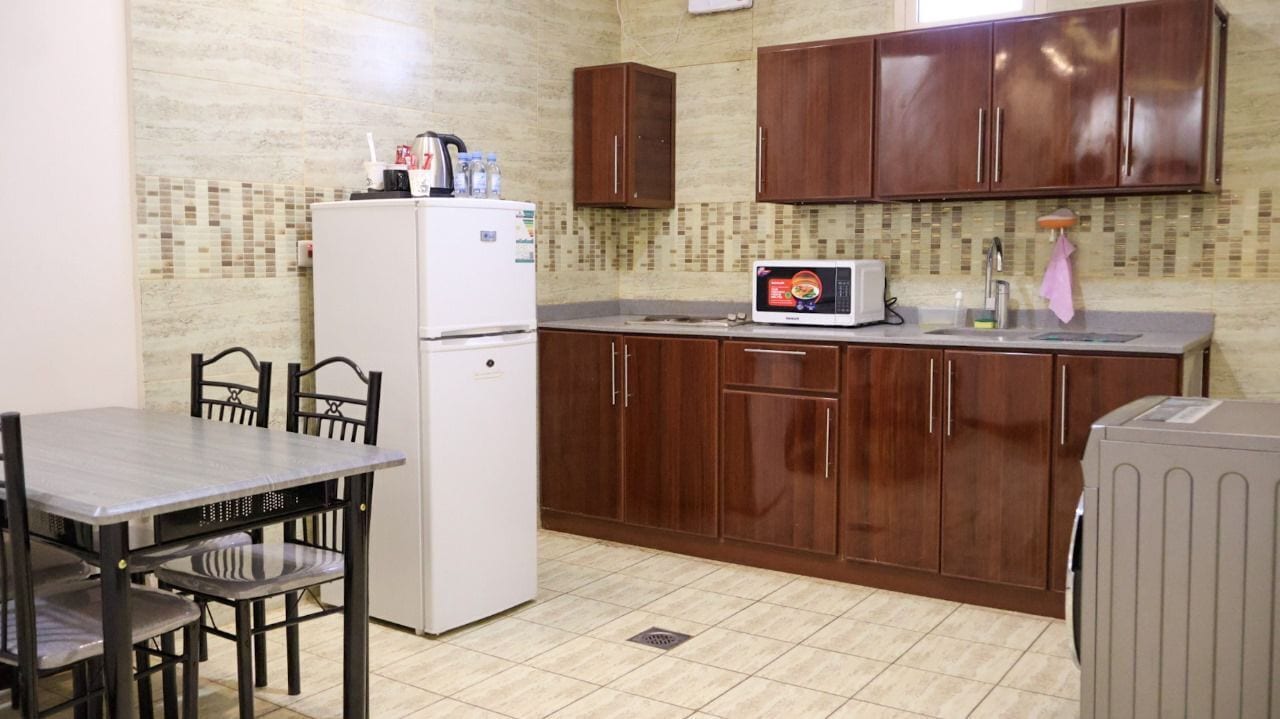 Cocina compacta con refrigerador, microondas y armarios de madera.
