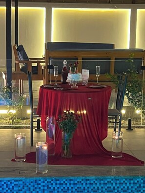 A dining table set with a red tablecloth, candles, and a vase with flowers. - تميُّز الاقامة للشقق المخدومة Tamyoz Aqama for Serviced Apartments (Ha'il)