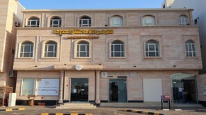 A building with multiple windows and a sign indicating it is a Tamyoz Alaqama Services Apartment. - تميُّز الاقامة للشقق المخدومة Tamyoz Aqama for Serviced Apartments (Ha'il)
