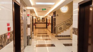 A hotel lobby with a marble floor, a staircase with decorative railings, and a sign indicating an exit. - تميُّز الاقامة للشقق المخدومة Tamyoz Aqama for Serviced Apartments (Ha'il)