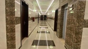 A hotel corridor with marble walls, a tiled floor, and a ceiling with linear lighting. - تميُّز الاقامة للشقق المخدومة Tamyoz Aqama for Serviced Apartments (Ha'il)