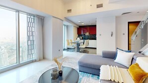A modern living room with a grey sofa, a glass coffee table, and a view of the city through large windows. - Cayan Tower - Smart One Bedroom Loft on High Floor (Dubai Marina)
