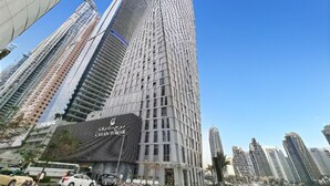 A tall skyscraper with a modern design, featuring a prominent 'CAYAN TOWER' sign at the base. - Cayan Tower - Smart One Bedroom Loft on High Floor (Dubai Marina)