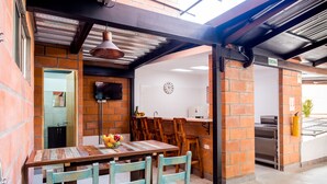 Un espacio comedor al aire libre de estilo rústico, con pared de ladrillo, mesa y sillas de madera.