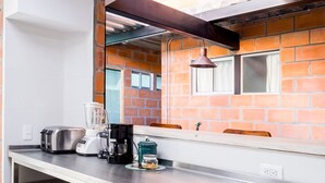 Una cocina con pared de ladrillo, una ventana, un fregadero y una encimera con licuadora, tostadora y cafetera.