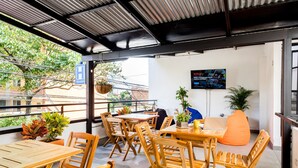 Un hostal con muebles de madera, una pantalla de televisión y plantas en macetas.