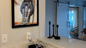 A kitchen with a marble countertop, a framed artwork of a rope, and a power outlet.