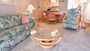 A living room with a floral sofa, a glass coffee table, and wooden chairs. - 2 BR 2 BA Ocean Front building Pool and Tennis (Ocean City)