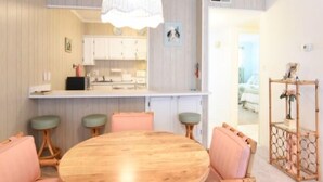 A compact kitchen with white cabinets, a wooden dining table, and a hanging light fixture. - 2 BR 2 BA Ocean Front building Pool and Tennis (Ocean City)