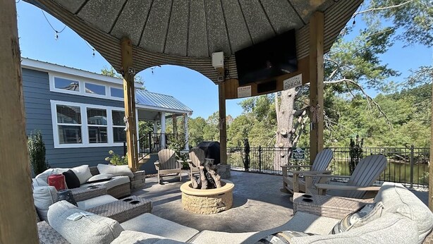 Un espacio de estar al aire libre cubierto con muebles de mimbre y una chimenea.