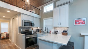 Una cocina moderna con armarios blancos, estufa de acero inoxidable, microondas y una isla grande con taburetes de bar.