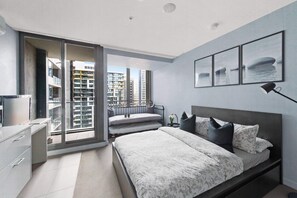 Une chambre moderne avec un grand lit, une table de chevet, un bureau et une vue sur la ville, accessible par une porte coulissante.
