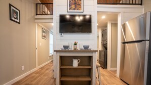A compact kitchen with a built-in TV, a stainless steel refrigerator, and a wooden countertop.