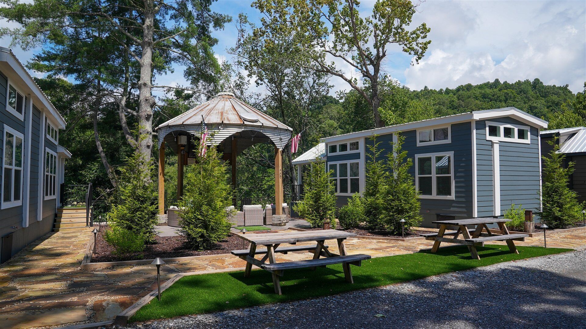 A residential area with a gazebo, picnic tables, and small cabins.