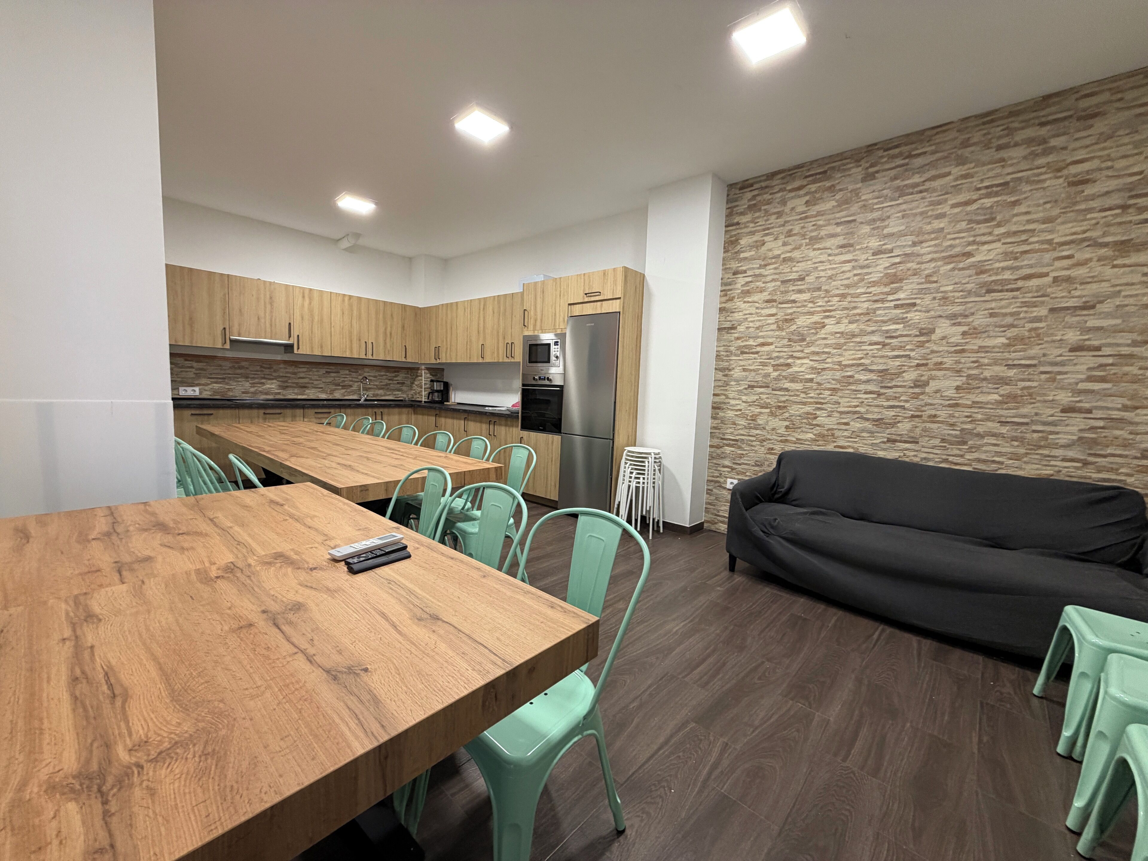 Een moderne keuken met houten kastjes, een centraal eiland en een eethoek met groene stoelen.
