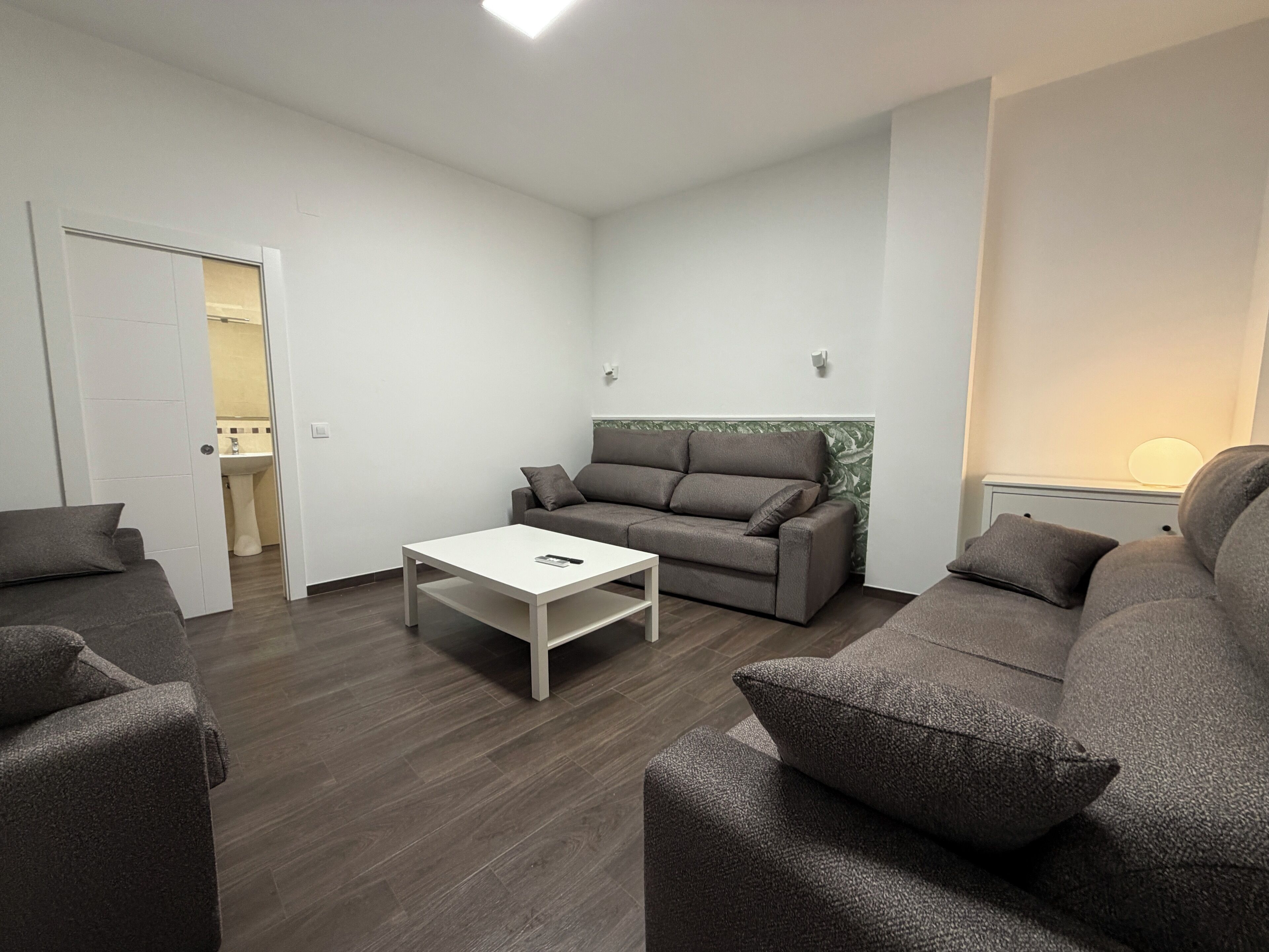 Ein modernes Wohnzimmer mit einem grauen Sofa, einem weißen Couchtisch und einem grauen Sessel.