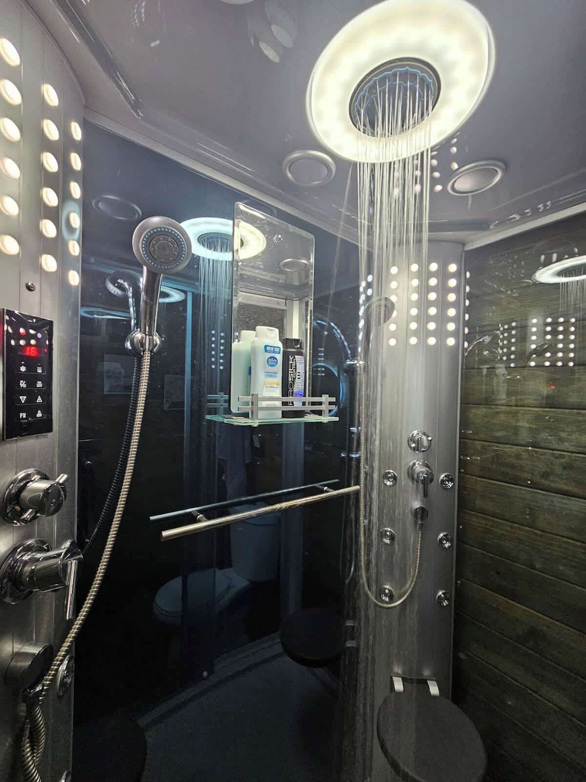 Une douche moderne dotée d’un panneau de commande, d’un espace clos en verre et d’un mur en bois.