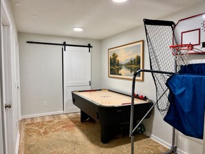 A room with a foosball table, a basketball hoop, and a door. - Charming Private Suite with Game Room in Athens (Athens)