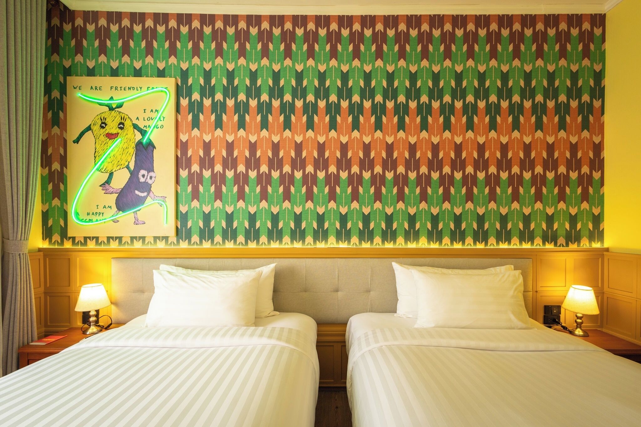 Quarto de hotel com duas camas, parede estampada e um cartaz.