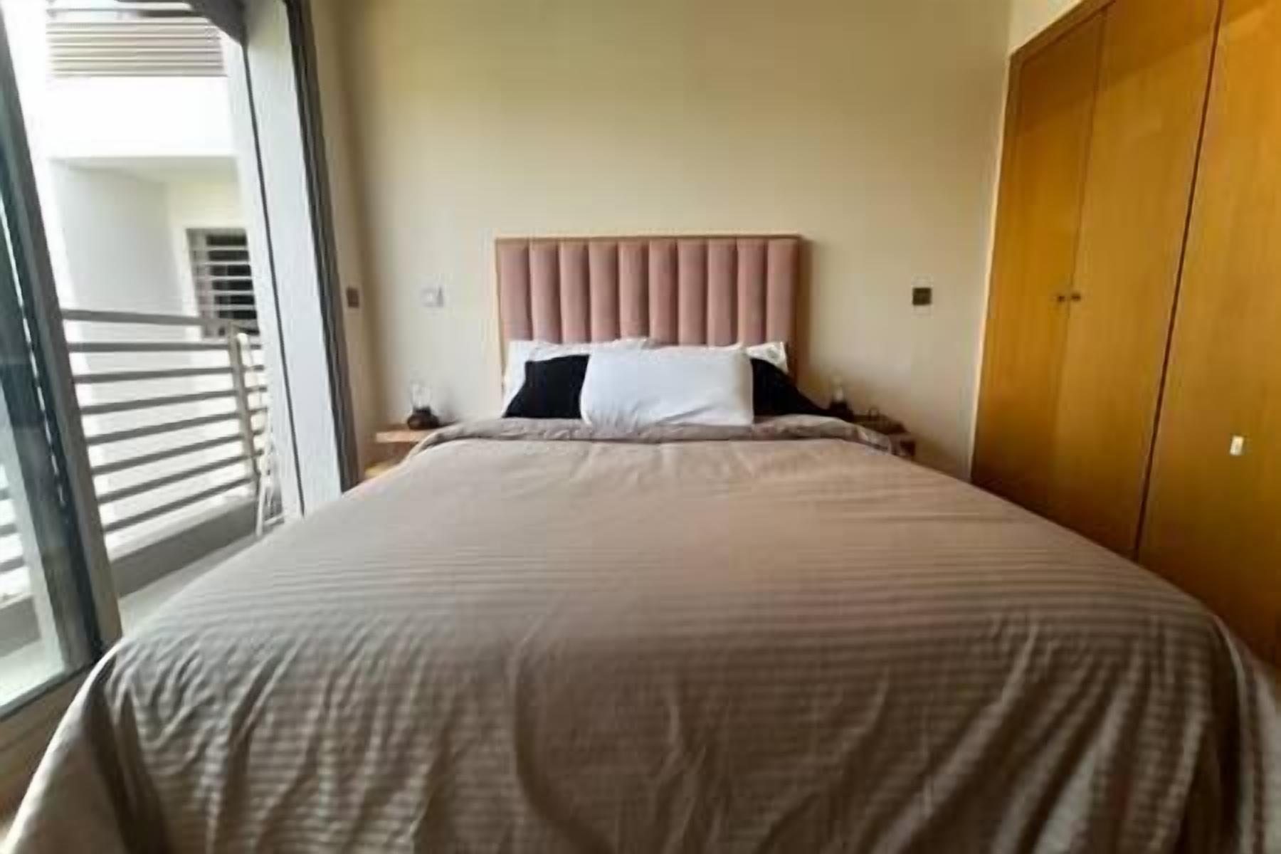 Een hotelkamer met een groot bed, een houten garderobe en uitzicht op het balkon.