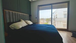 A bedroom with a bed, a headboard, and a large sliding glass door leading to an outdoor balcony.