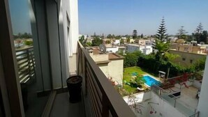 A balcony with a view of a residential area, including houses and a swimming pool.