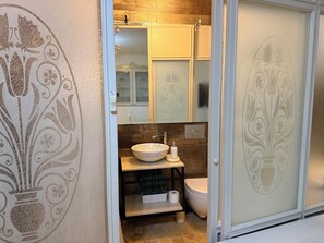 A bathroom with a white sink, a toilet, and a decorative wall. - Studio Oratorio (Rovinj)
