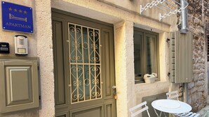 A building entrance with a green door, a 'PARTMAN' sign, a security keypad, and a small table with white chairs outside. - Studio Oratorio (Rovinj)
