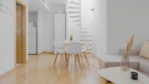 Un espacio habitable moderno y minimalista con comedor, escalera y zona de estar.