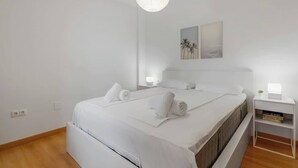 Habitación de hotel minimalista con una cama grande, mesitas de noche y una obra de arte colgada en la pared.