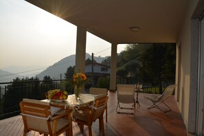 A balcony with a table set for dining, chairs, and a sun lounger. - Spacious apartment with a panoramic terrace, 10 minutes from Lake Iseo. (Colognola)