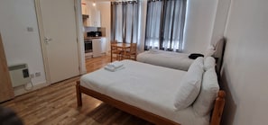 Habitación de hotel con dos camas, una kitchenette pequeña y un área de comedor.