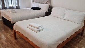 Two single beds with white linens and pillows, a wooden headboard, and a wooden floor. - Urban Retreat Studio Camberwell Zone 2 (London)
