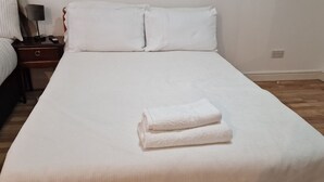 A neatly made bed with white linens and a folded towel on the bed. - Urban Retreat Studio Camberwell Zone 2 (London)