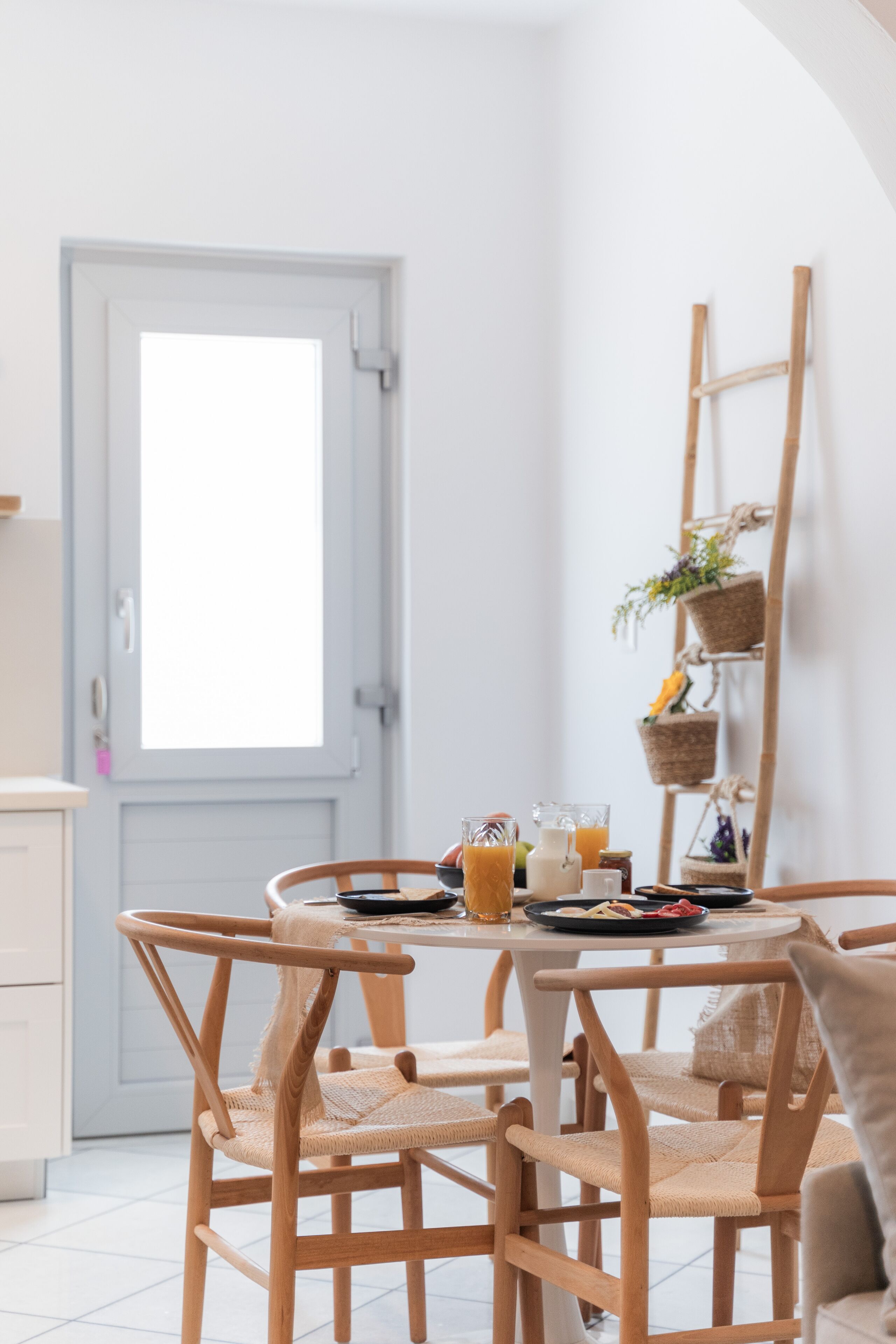 Un coin repas avec une table ronde, des chaises en bois et une porte blanche.
