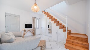 Ein modernes Wohnzimmer mit einer Couch, einem Fernseher, einer Holztreppe und einem großen Fenster.